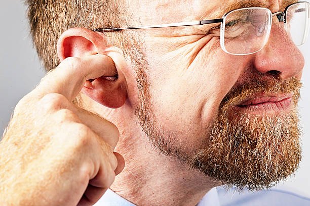 Man pointing to his ear due to earwax discomfort